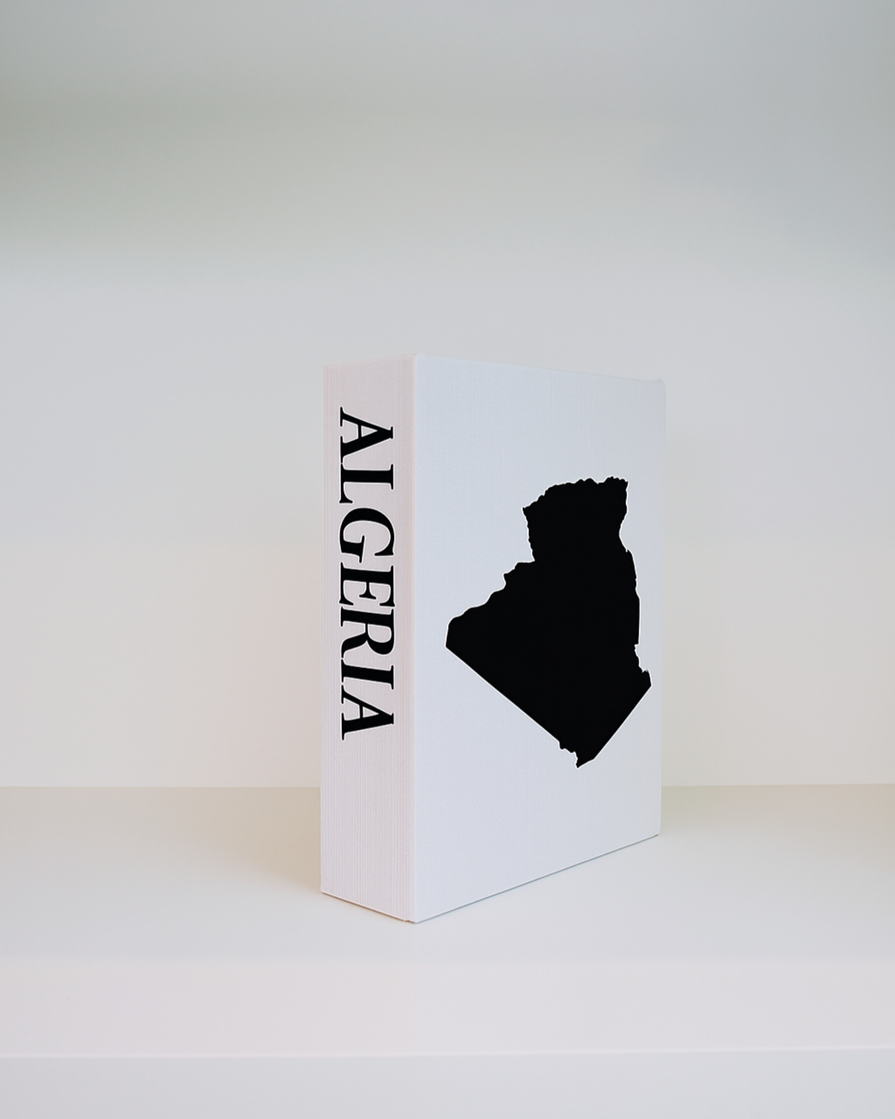 White book with black silhouette of Algeria on a white background